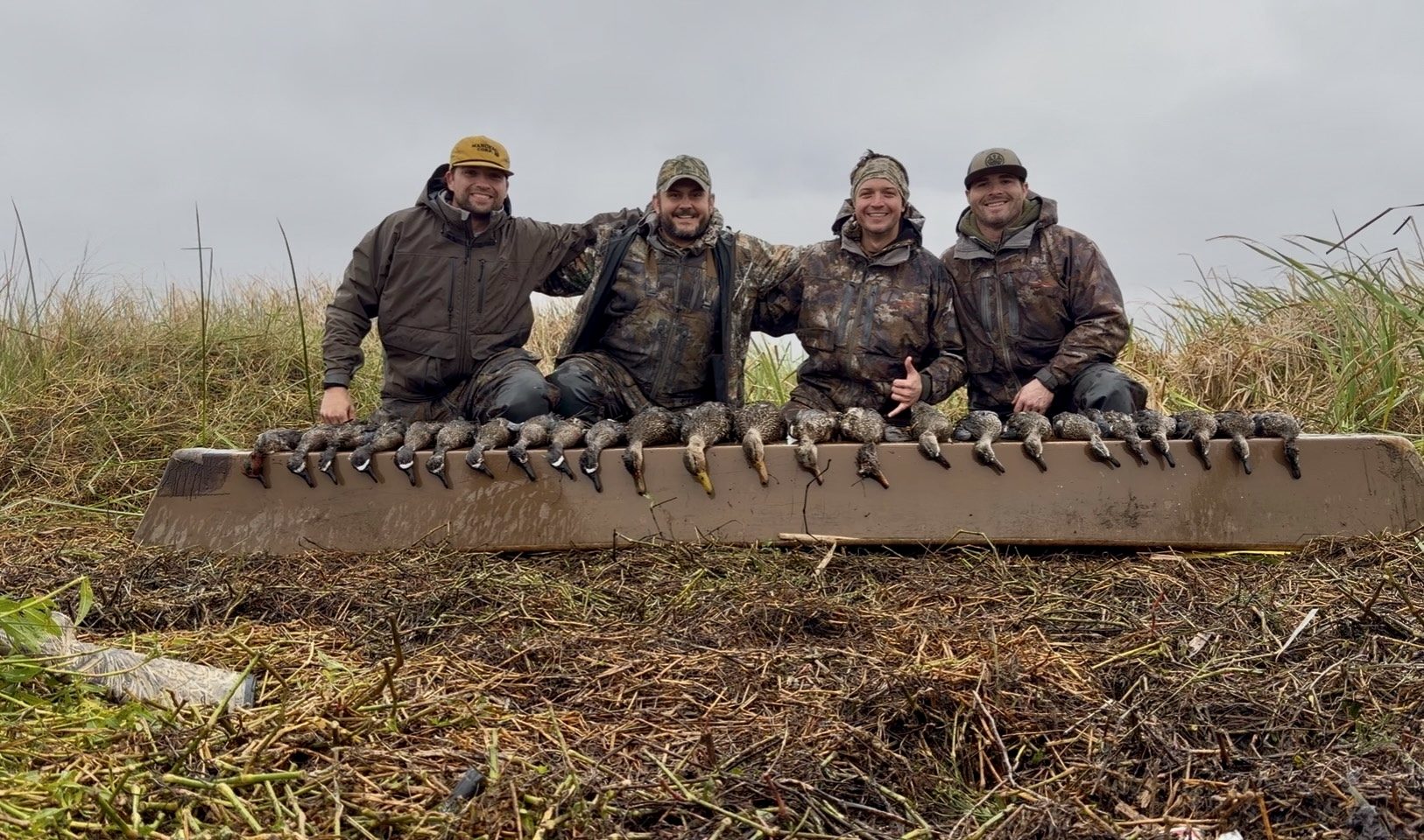Four hunters behind a full limit of ducks in the marsh