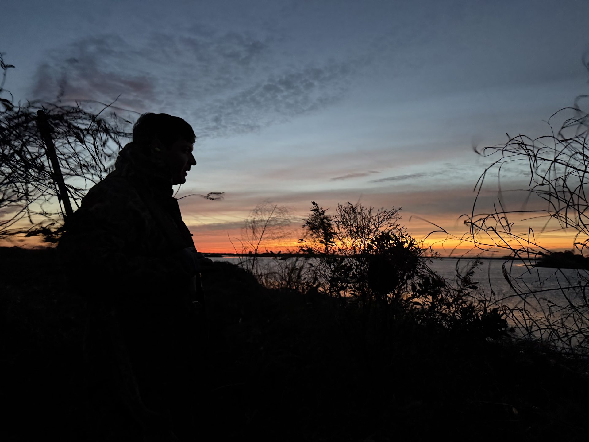 A hunter watching the sun come up over the marsh